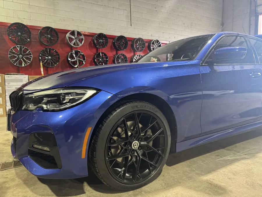 BMW 3 Series on aftermarket wheels in front of the Taylor Tire wheel display